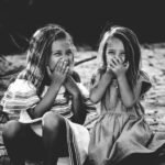 grayscale photography of two girls closing their mouths