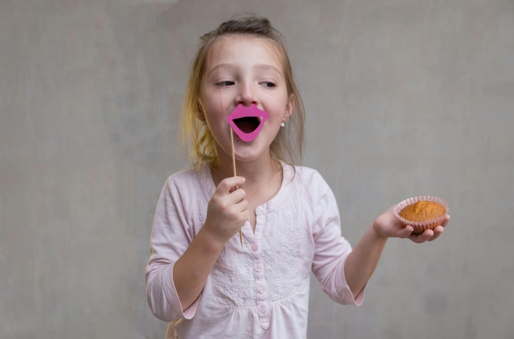 a little girl holding a donut and sticking a pink tongue out